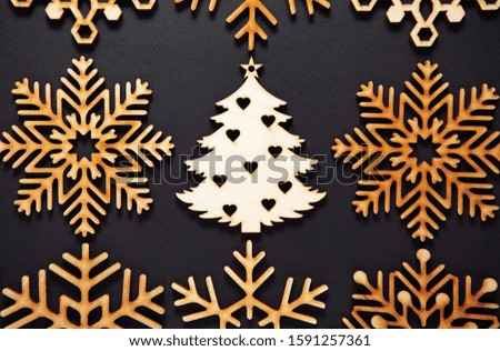 Flat lay wooden Christmas tree toy on black background.Rustic handmade decorations shot from above.Beautiful hand crafted decor elements for winter holidays