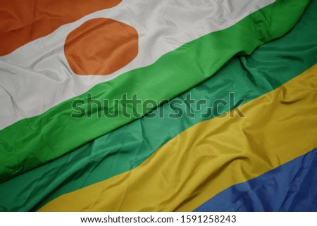waving colorful flag of gabon and national flag of niger. macro