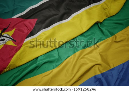 waving colorful flag of gabon and national flag of mozambique. macro