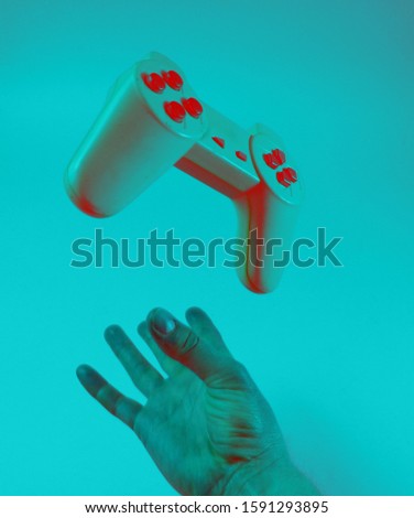 Male hand throwing up a gamepad, holographic duotone light.