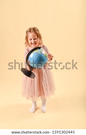 Smiling cute schoolgirl. laughing baby girl with a globe on a pink background. in the studio on a pink background. The concept of studying at school, or travel. copy space