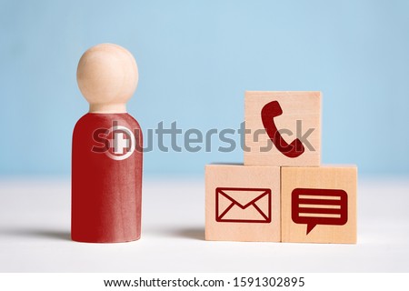 The concept of an abstract doctor with a sign of medicine with contact icons - phone, mail, messenger. A wooden figurine with cubes on a blue background. Close up.