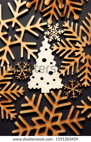 Beautiful handmade wooden Christmas Tree toy in flat lay on black background.Vertical postcard image with hand crafted toys made from wood.New Year decor made from ecological materials