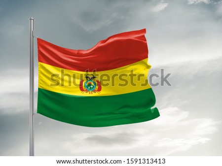 Bolivia national flag cloth fabric waving on beautiful grey sky.