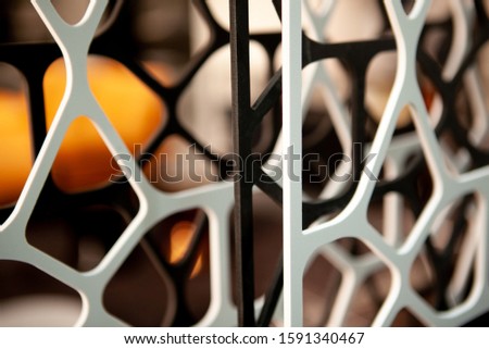 Close-up photo of red and blue metal grid structures with elliptic openings over textured white glass. Abstract modern architecture, construction industry or industrial interior background.
