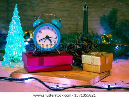 
It's time for gifts. Holiday decoration on wooden background. The clock as a symbol of time for giving