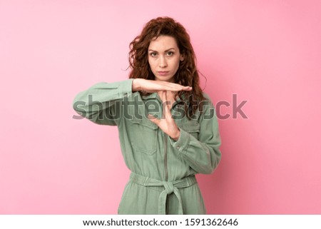 Young pretty woman over isolated pink background making time out gesture