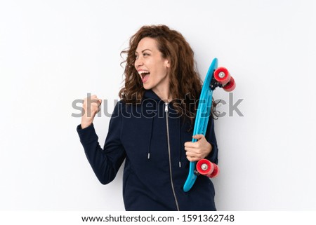 Young pretty woman over isolated background with skate and making victory gesture
