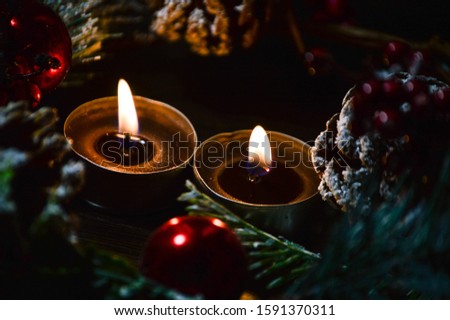 New Year and Christmas decor on a brown background of cones, winter berries, spruce branches, toys and burning candles.
