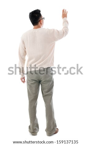 Rear view of Asian man hand touching on transparent virtual screen, space for text/button, full length standing isolated on white background.