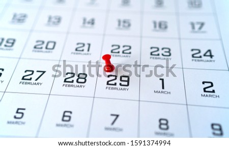 Close up of a part of the calendar of February and March, in black and white. A red pin is marking Leap Day - February 29.  Royalty-Free Stock Photo #1591374994