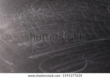 Closeup blackboard with dust of rubbed chalk in fade light as background