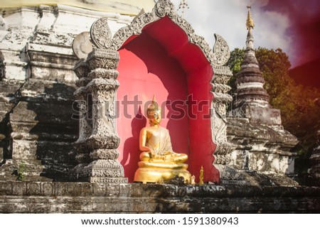 Detail of the chedi of Wat Buppharam temple with an Earth Touching Buddha Sitting statue with golden cloths. Chiang Mai
