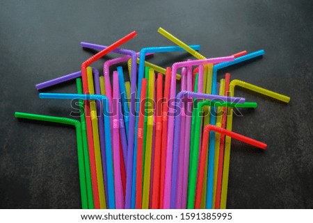 Close up of Multicolored plastic cocktail tubes lie in a pile on a dark, almost black background