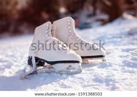 White ice skates on the snow in the park. Pleasure girl skated and went for coffee and left ice skates in the snow