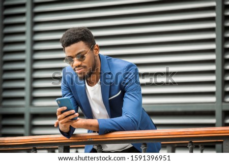 handsome african man in a blue jacket with a phone in his hand