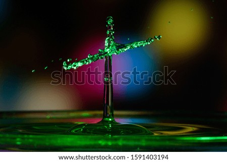 Double falling water drops and exposed with beautiful colored flash lights with a matching colored background . The  splash of  drops occurs in the collision between an upstanding and a falling drop
