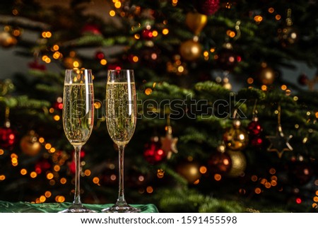 Two glasses of sparkling champagne that's on the back of a Christmas tree