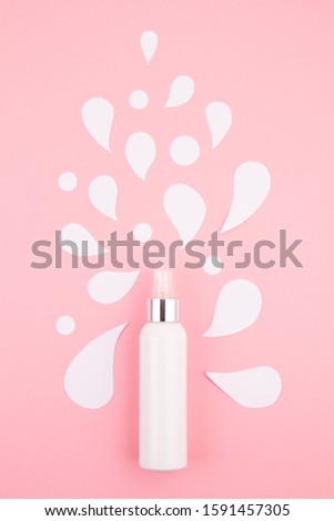 Cosmetic bottle on pastel pink modern paper background with paper cut splashes. Mock-up for product package branding, personal hygiene, skin care concept