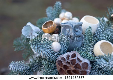 Christmas flower 
composition of spruce branches, cotton flowers, cinnamon, Christmas glass balls, ribbons and gray Ceramic owl for gift . New Year decor for an interior