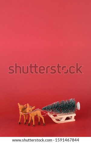Christmas or New year background design. Reindeer with winter sleigh and Christmas tree on red background. Christmas background with space for text.