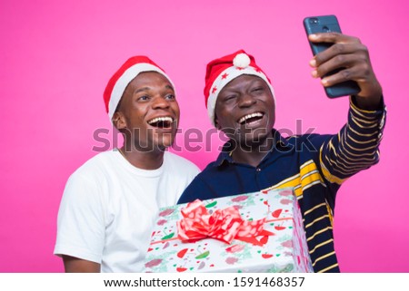 overexcited black african Lgbt couple doing video call holding Christmas  gift 



