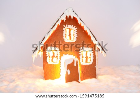 The hand-made eatable gingerbread house with light inside and snow decoration