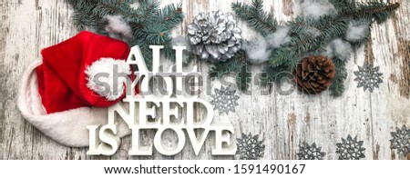 All you need is love logo with Christmas theme on woood background with Santa hat.