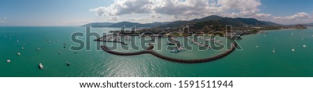 Airlie beach waterfront aerial view. Dramatic DRONE view from above. Marina town with yachts and boats in sea water. Mountain landscape background. Shot in Whitsundays Islands, Queenstown, Australia.