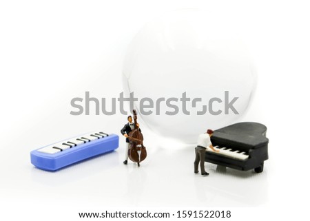 Miniature people : pianist playing piano and Violinist Man with mini world glass,playing musical instrument concept.