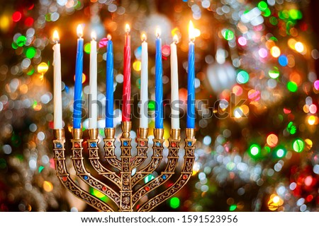 Menorah with burning candles for Hanukkah on sparkle background with defocused lights. Jewish holiday.