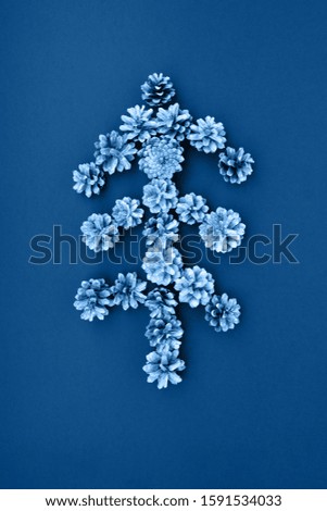 Christmas tree made of white painted pine cones on a blue background. New Year Concept.