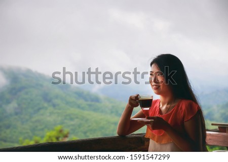 Vintage Photography style of beautiful Asian traveler woman drinking coffee and watching fog or mist at the restaurant on the mountain, travel theme portrait.