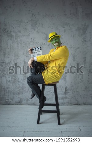 A man in a light yellow suit on top of a mask, considers it necessary to fool around and cheerful naughty likes tricks