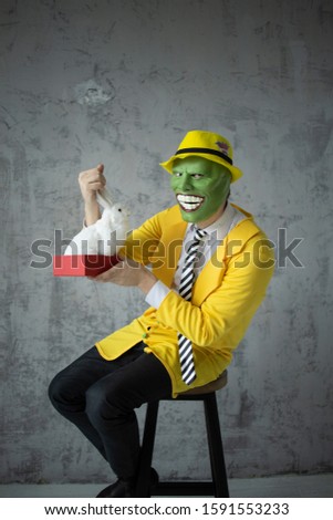 Mask yellow suit, green mask, as in the movie, shooting a movie in the hands of an artificial hare looks at him and wants to eat