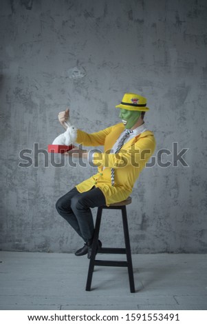 A man in a light yellow suit on top of a mask, loves to fool around and a cheerful naughty can not tricks