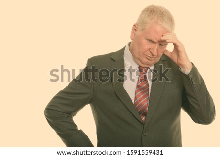 Studio shot of stressed mature businessman looking down while thinking
