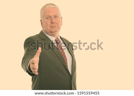 Studio shot of mature businessman giving handshake