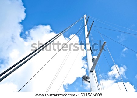 Furled fore sails and tall white mast of a modern maxi sailing yacht.