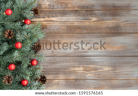 Christmas border with fir branches, red balls and cones on a wooden background. Happy new year. Space for text. Winter concept. Greeting card. Copy space, template. Top view, flat lay.