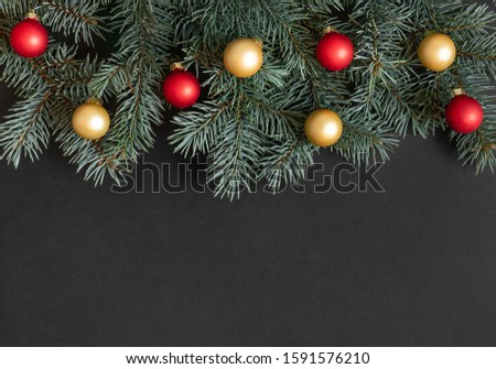 Christmas border with fir branches, red and gold balls on a black background. Happy new year. Space for text. Winter concept. Greeting card. Copy space, template. Top view, flat lay.