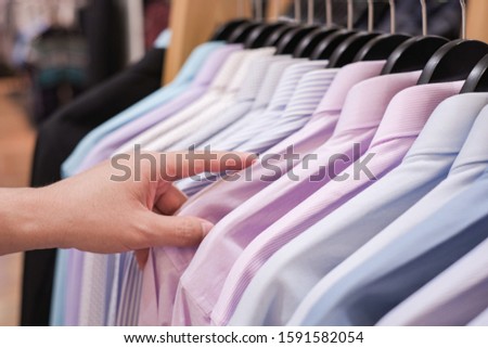 Cropped Hand Of Man choosing Men's shirts in clothing store