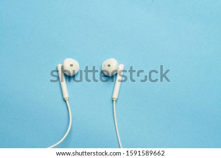 Close up ear bud or earphone over blue background. Music Copyspace Concept