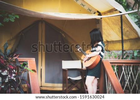 happy young cute female Asian woman Japanese girl women hipster play guitar at tent camping campfire 
party at beautiful blue sky scenery river lake waterfall green forest Kanchanaburi, Thailand
