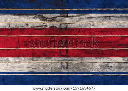National flag  of Costa Rica on a wooden wall background. The concept of national pride and a symbol of the country. Flags painted on a wooden fence with a rope