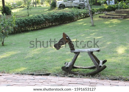 Rocking horse made of old wood on the courtyard, in the middle of the garden.  Vintage park furniture