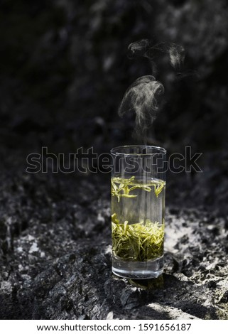A cup of hot green tea on rock in sunlight. Royalty-Free Stock Photo #1591656187