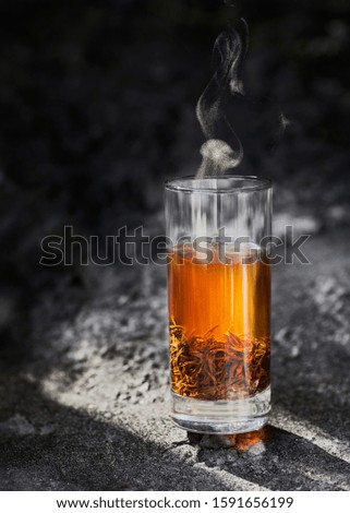 A cup of black tea on rock in sunlight. Royalty-Free Stock Photo #1591656199