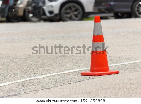 an orange traffic cone on the asphalted road in the car park