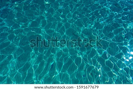 Clear sea water can be seen down to the sandy beach with white watermark.